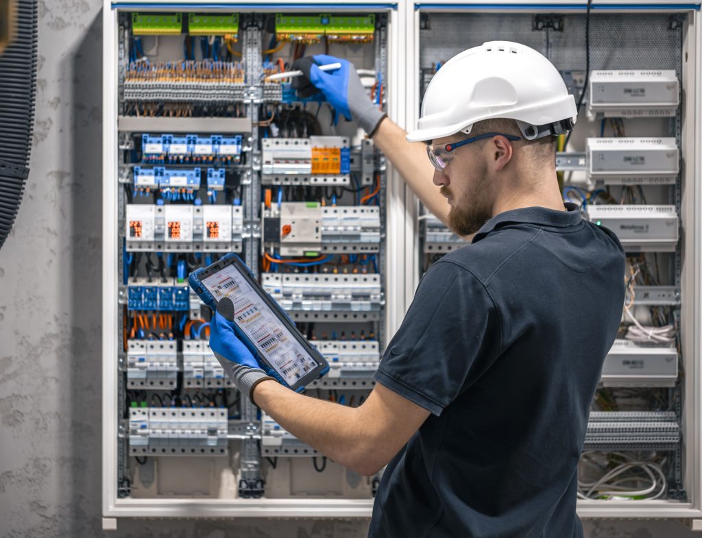 The electrician is performing maintenance on commercial electrical panels