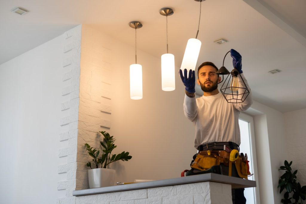 A licensed technician installing a light fixture in a client's home